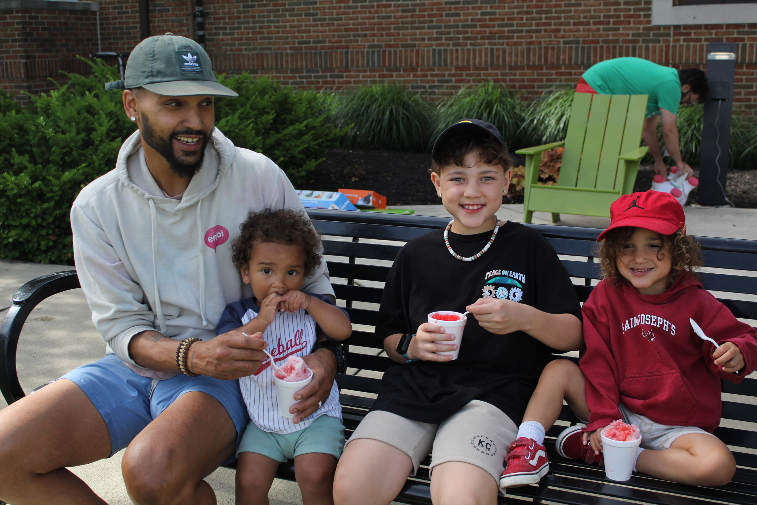 Adult and kids enjoying slushies on a park bench